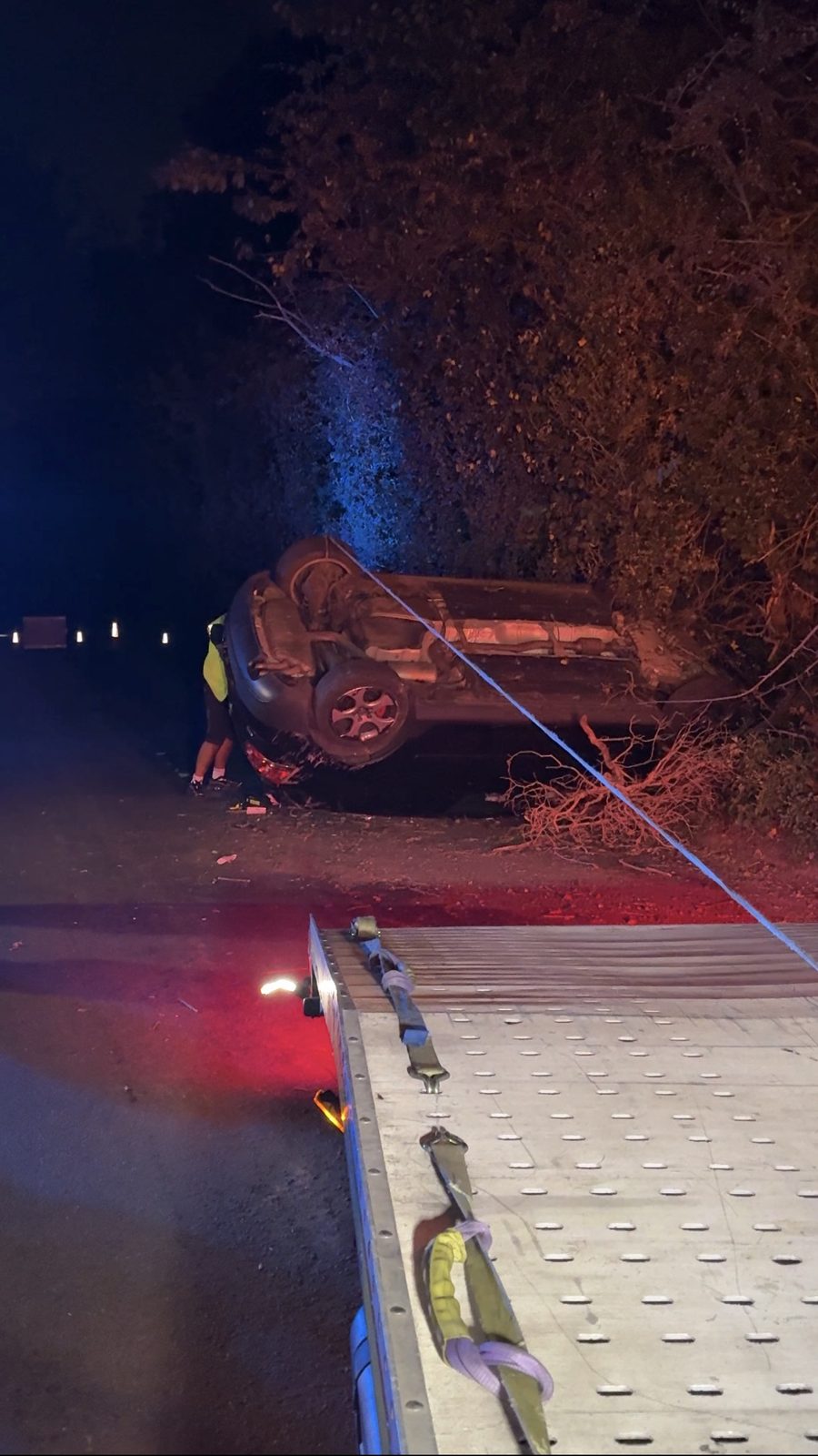 Vehicle on its side being recovered at night
